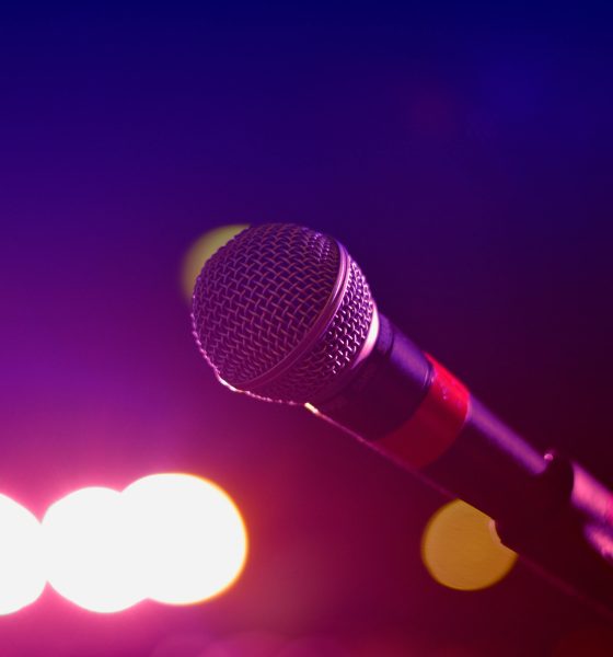 Colorful stage lighting highlights a microphone in a close-up view, perfect for music and performance themes.